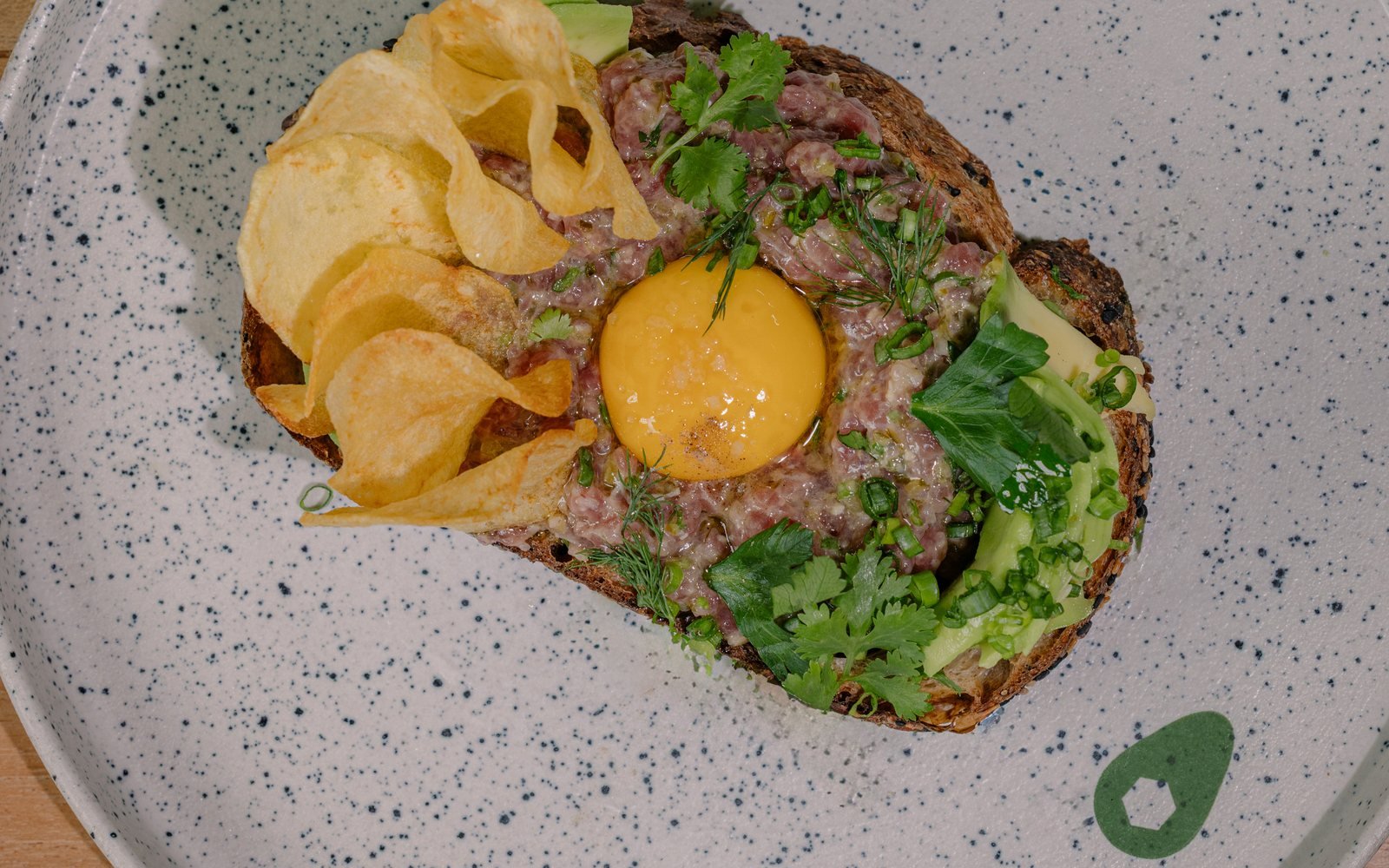 Avocado toast with egg, herbs, and crisp toppings at The Avocado Factory